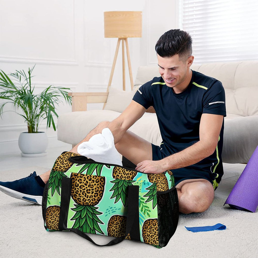 A man sits on a carpeted floor in a bright living room, placing a white towel into a black duffel bag with an ornate gold paisley pattern. The room features a beige sofa, a wooden floor lamp, and a potted plant.
