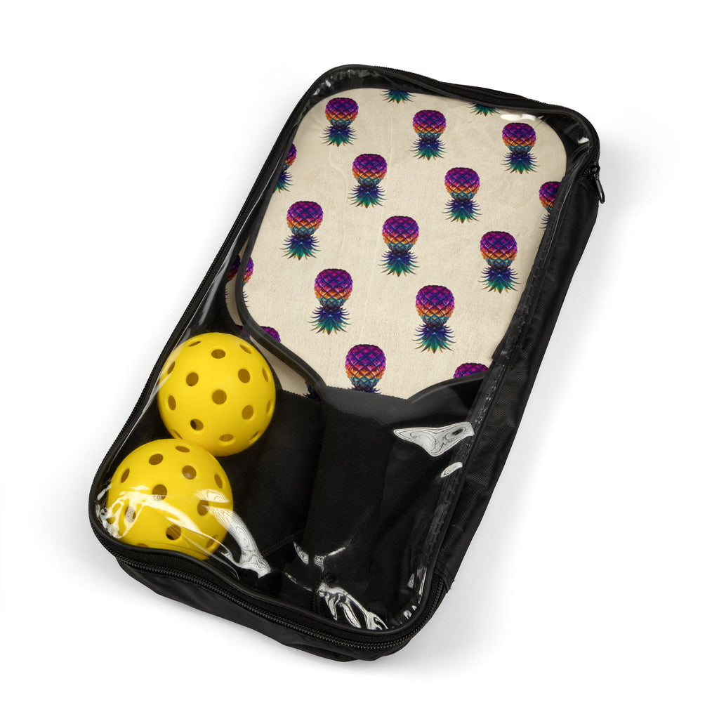 Colorful pineapple pickleball paddles beside two plastic balls, ready to pack in the included carry bag.