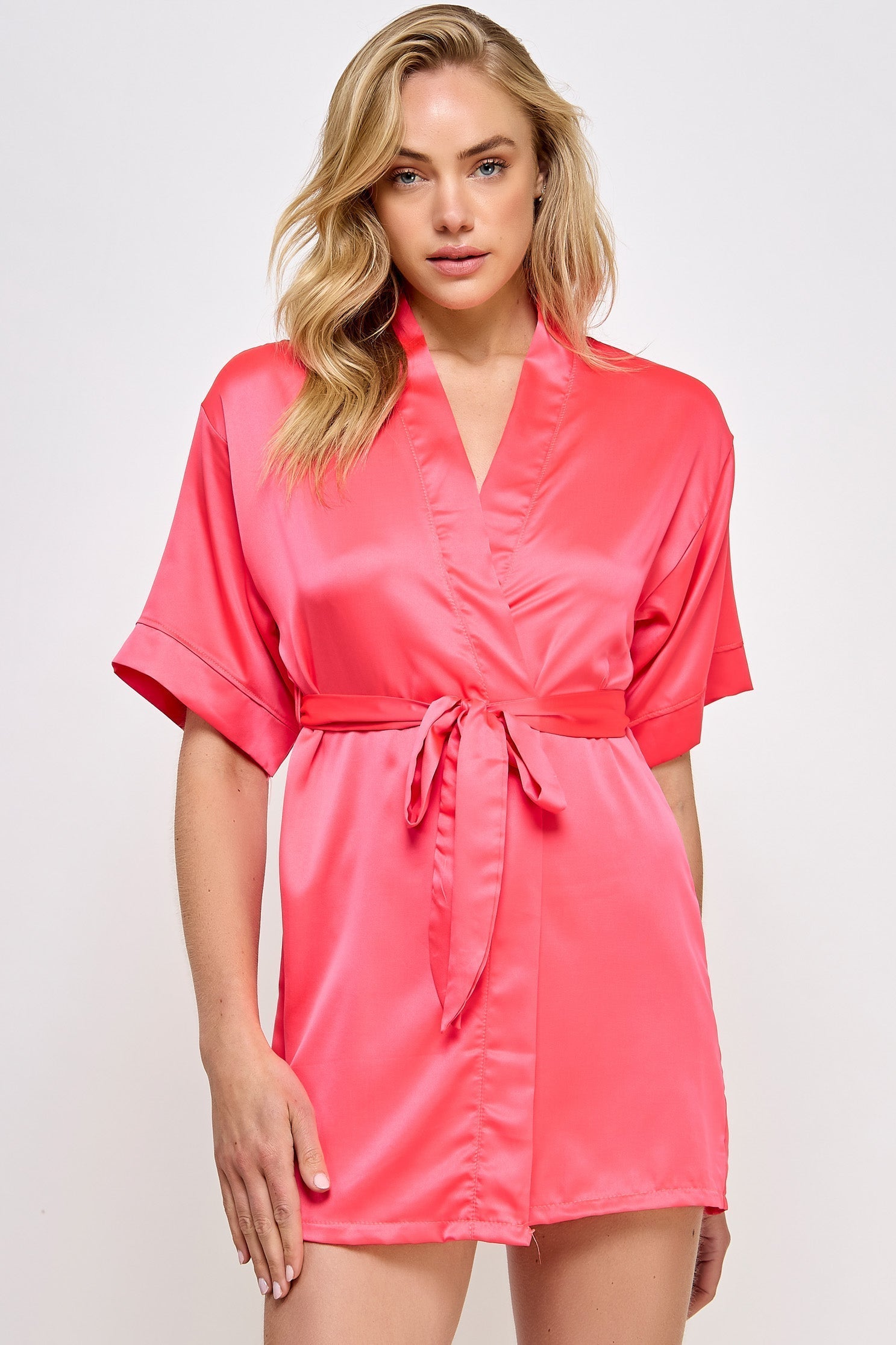 Woman wearing a pink satin robe against a white background