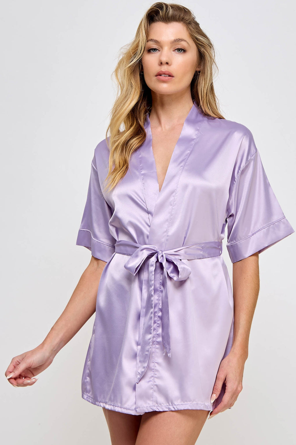 Woman wearing a light purple satin robe against a white background