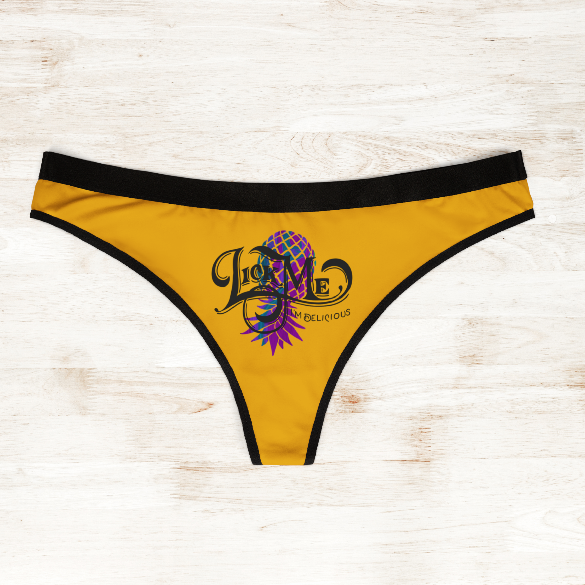 Yellow thong with black trim and colorful design on a light wooden surface