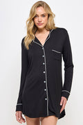 Woman wearing a black nightshirt with white buttons and trim on a white background