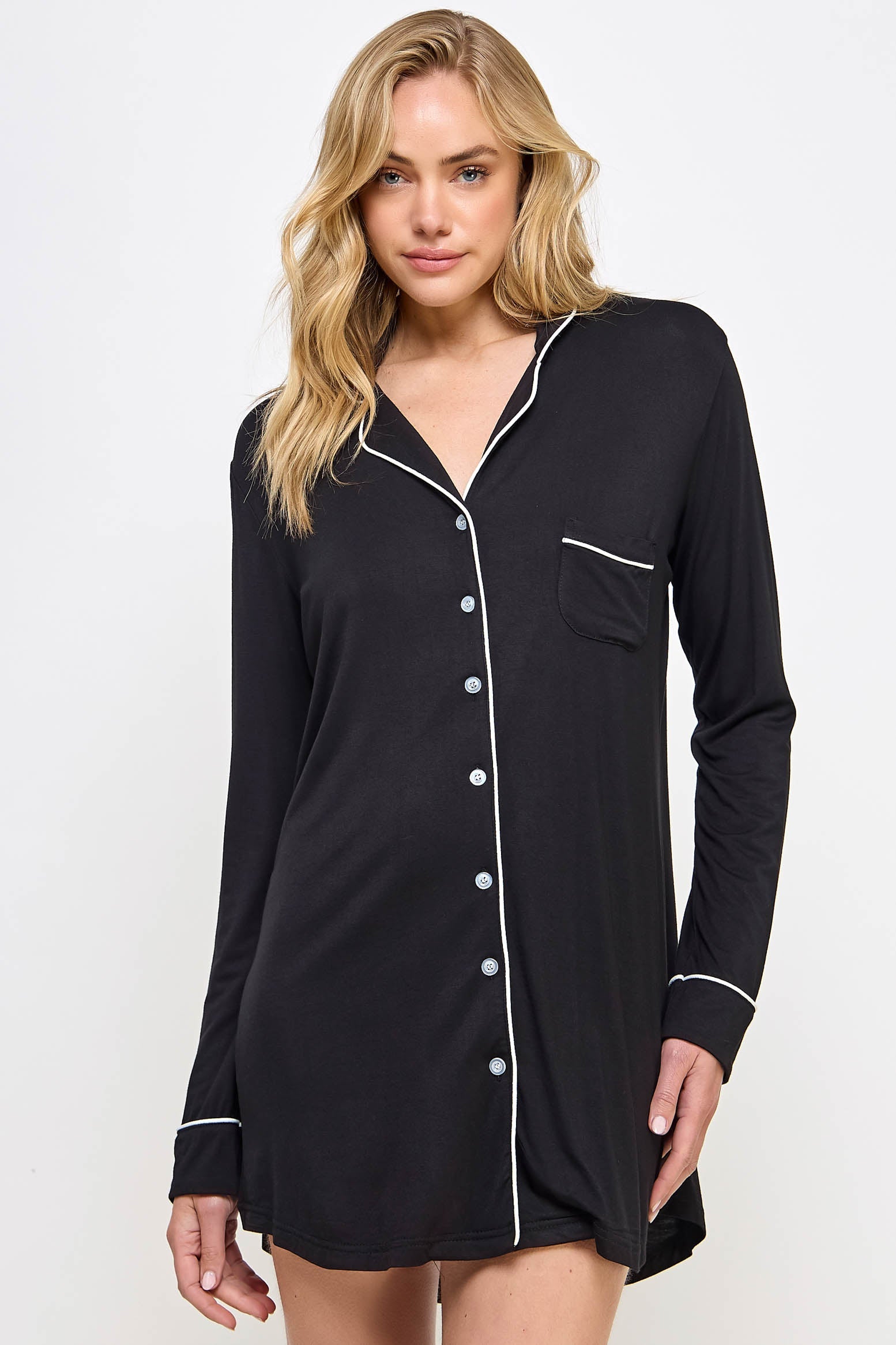 Woman wearing a black nightshirt with white buttons and trim on a white background