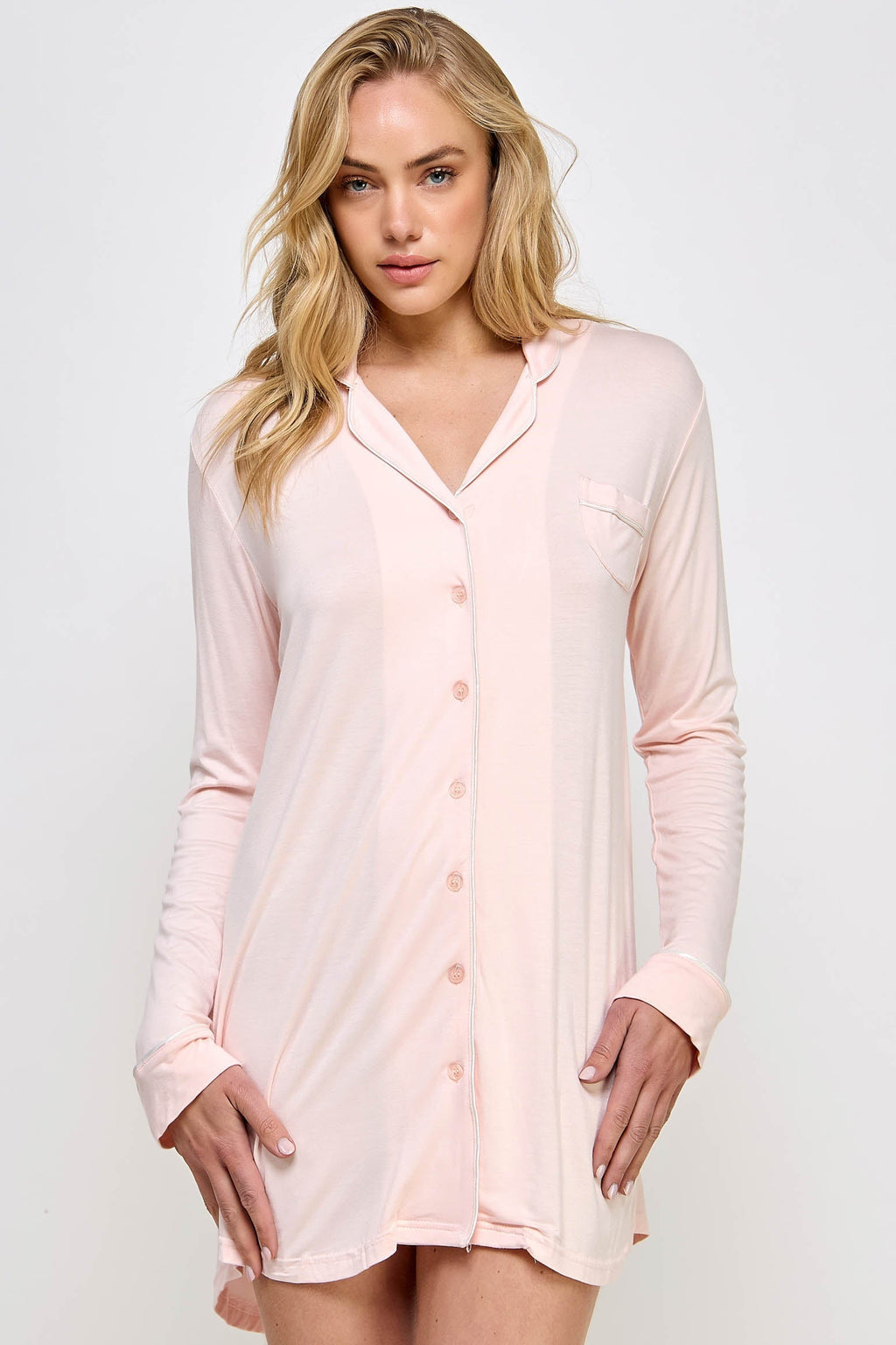 Woman wearing a light pink button-up nightshirt against a white background