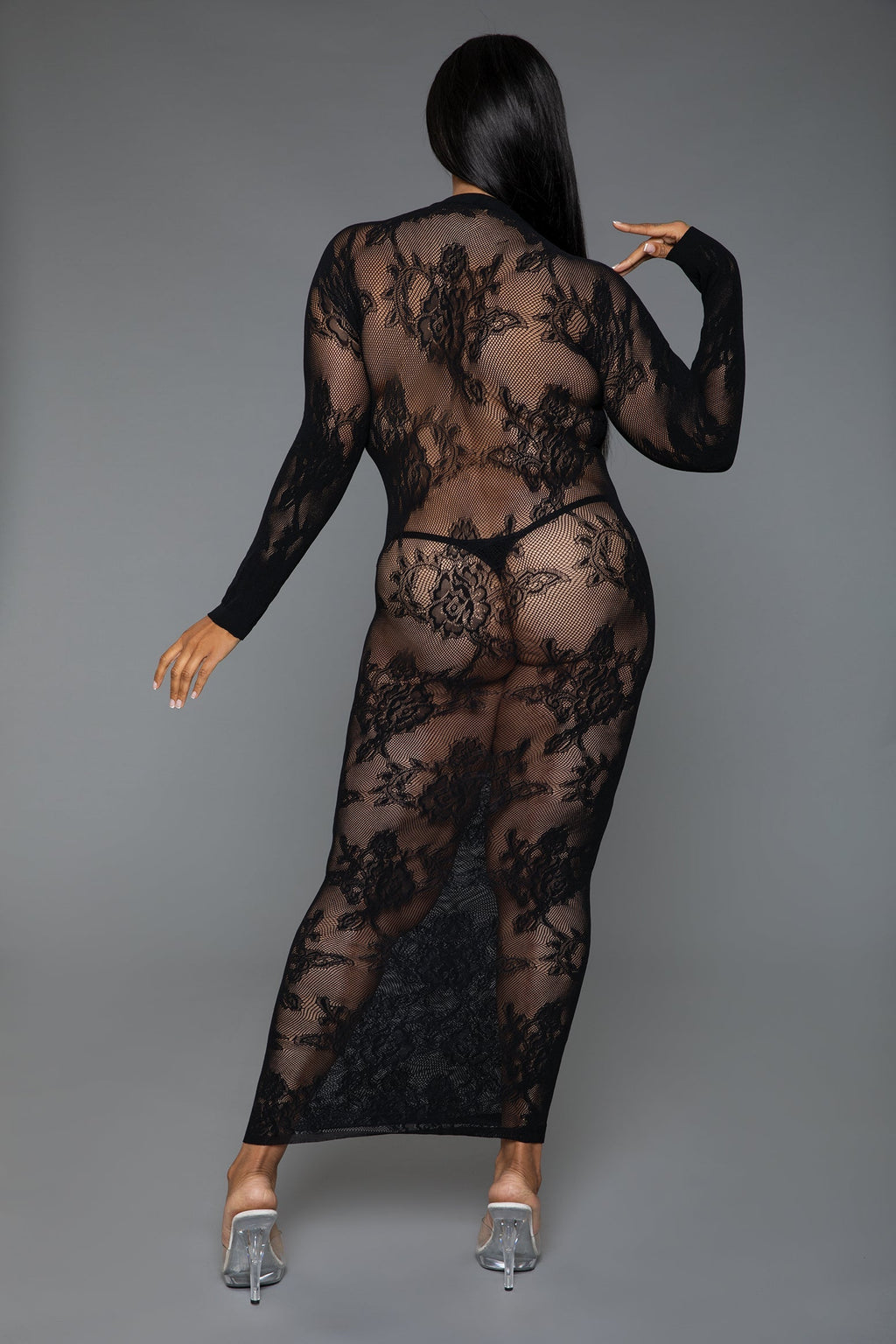 Person wearing a black sheer lace bodysuit on a gray background