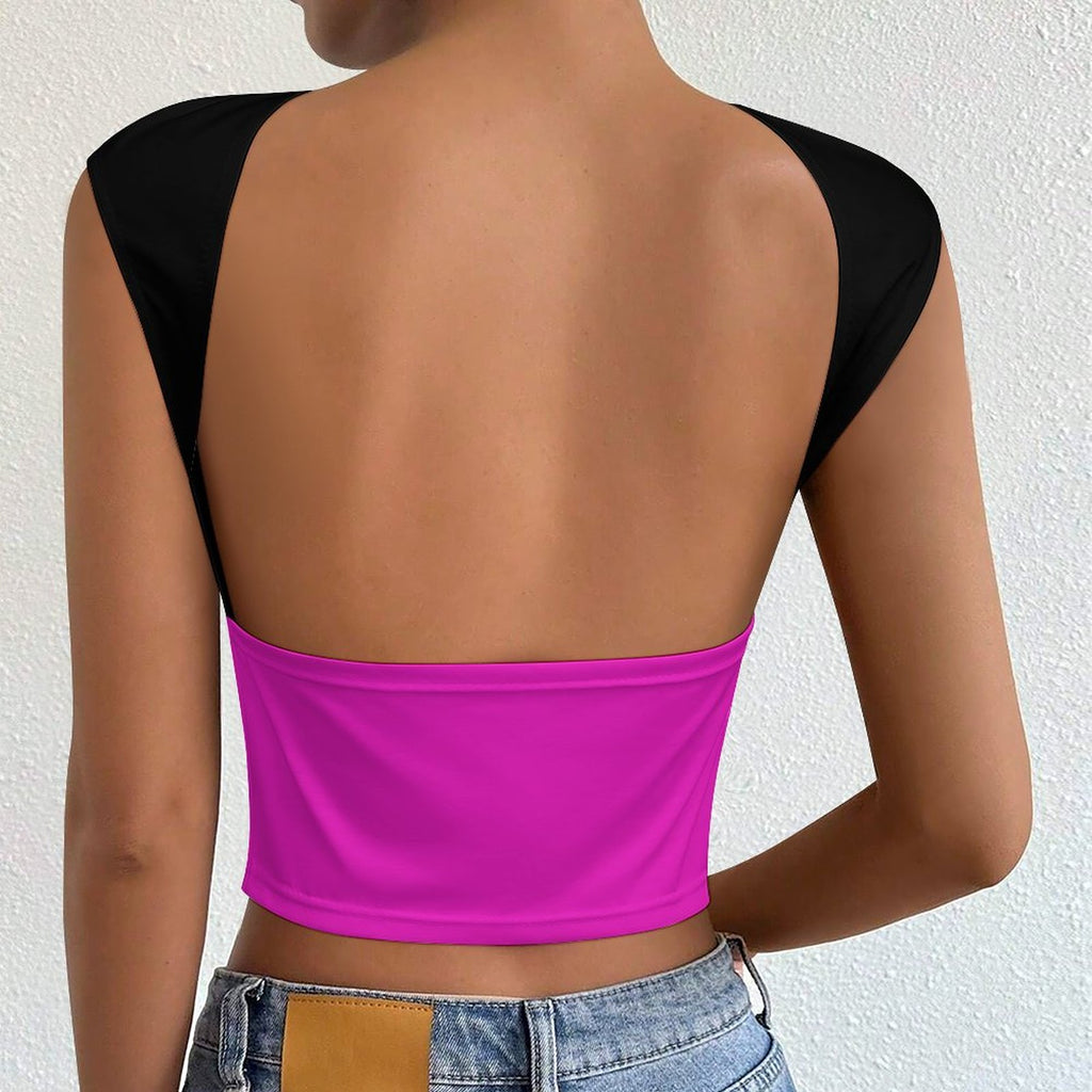 A woman shown from the back wearing a bright pink crop top with black shoulder panels, paired with light blue denim jeans against a textured off-white wall.