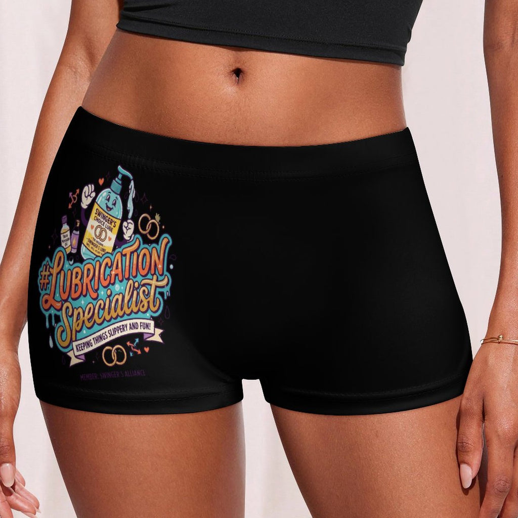Black boxer briefs with a colorful graphic on the left leg that reads '#Lubrication Specialist' with cartoon illustrations, shown on a model against a light neutral background.