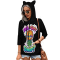 A woman wearing a black three-quarter sleeve hoodie with cat ears on the hood, featuring a colorful pineapple graphic and the text 'FULL SOFT SWAP?' on the front. She is also wearing denim shorts, sunglasses, and a brown shoulder bag against a plain white background.