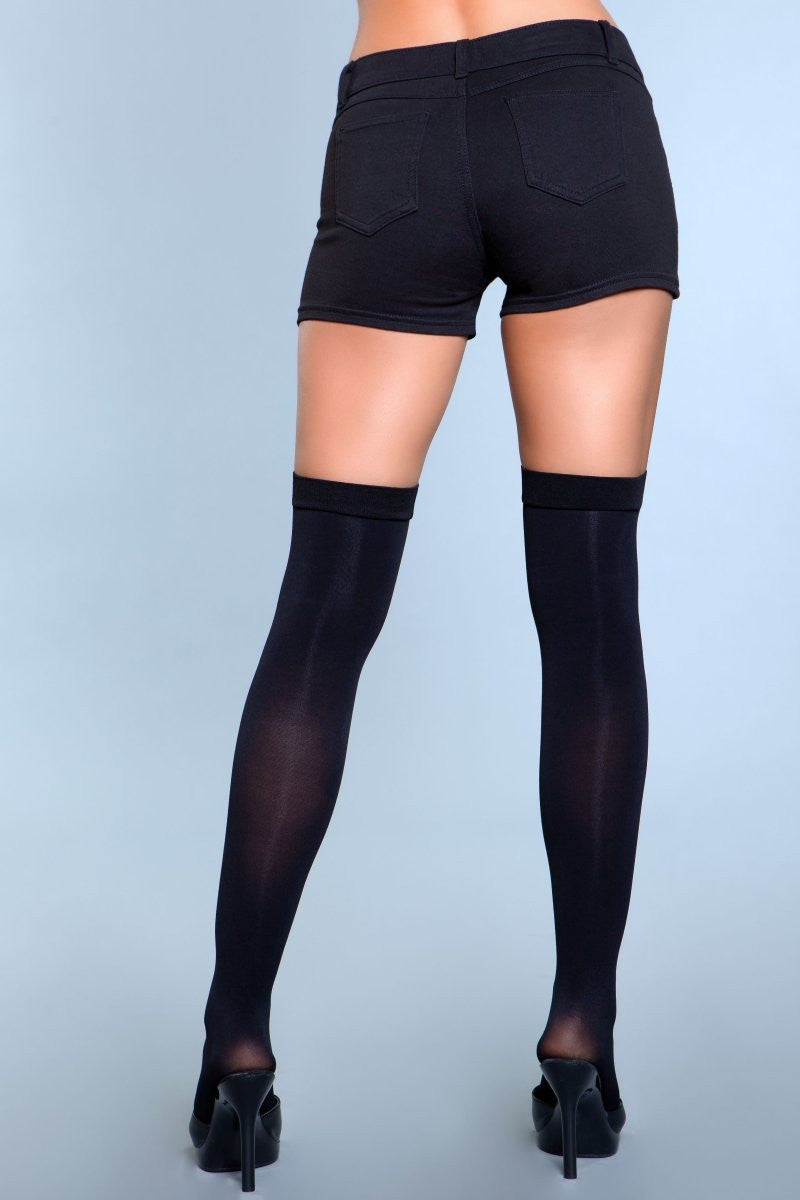 Person wearing black thigh-high stockings and black shorts on a light blue background
