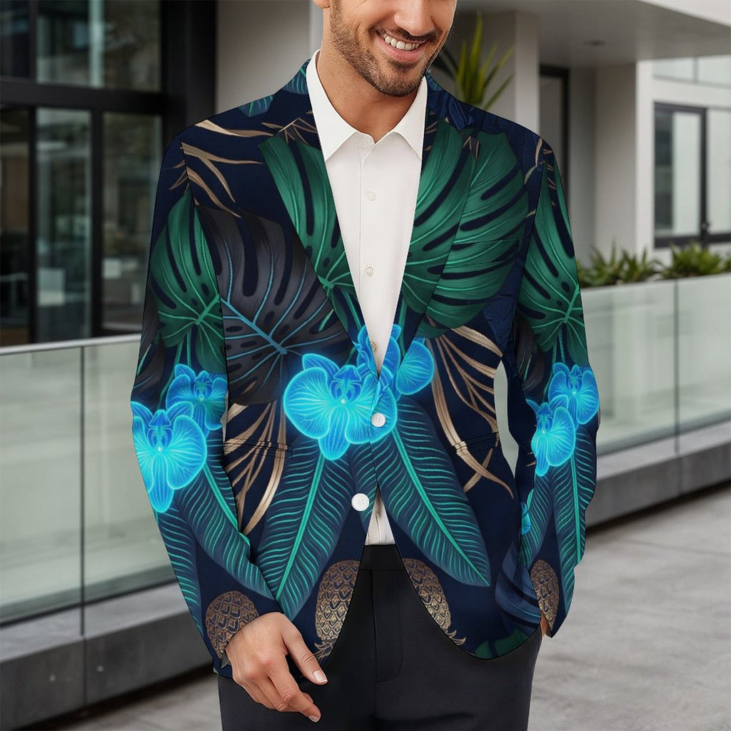 A man wearing a dark navy tropical print blazer with green palm leaves and bright blue orchids, styled over a white collared shirt and dark trousers, standing in front of a modern glass-walled building.