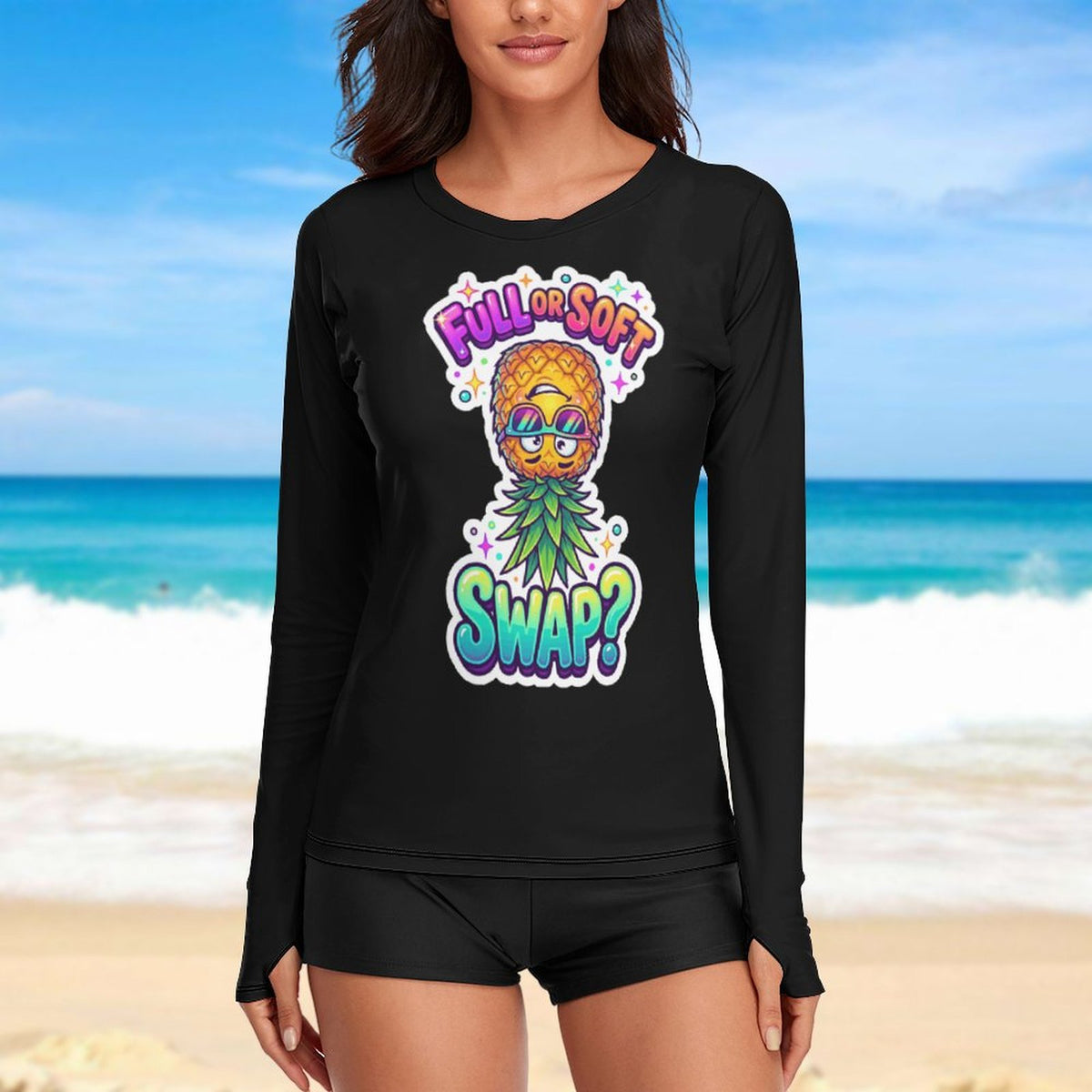 A woman wearing a black long-sleeve shirt with a colorful pineapple graphic and the text 'FULL OF SOFT SWAP?' stands on a beach with the ocean and sky blurred in the background.