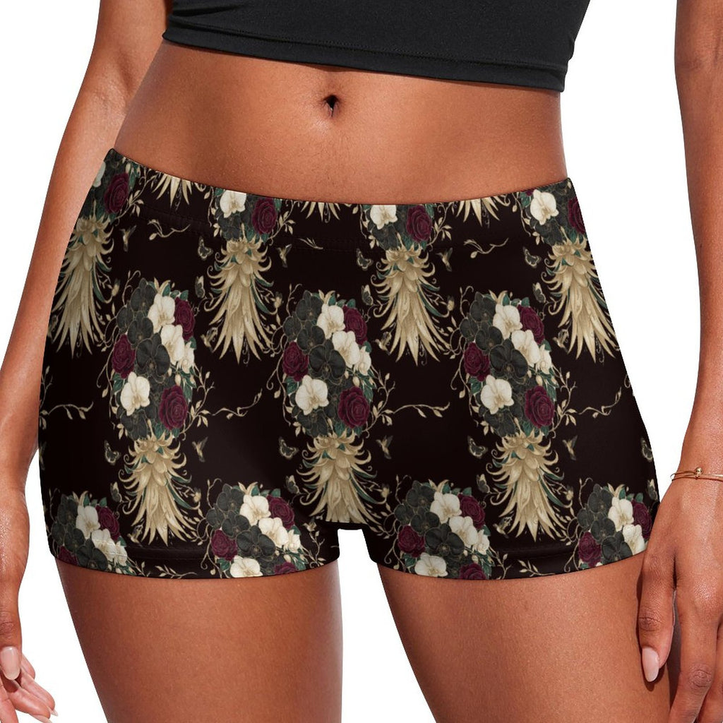 A close-up of a model wearing high-waisted boxer briefs with a dark brown background and a detailed floral and feather pattern in cream, burgundy, and green.