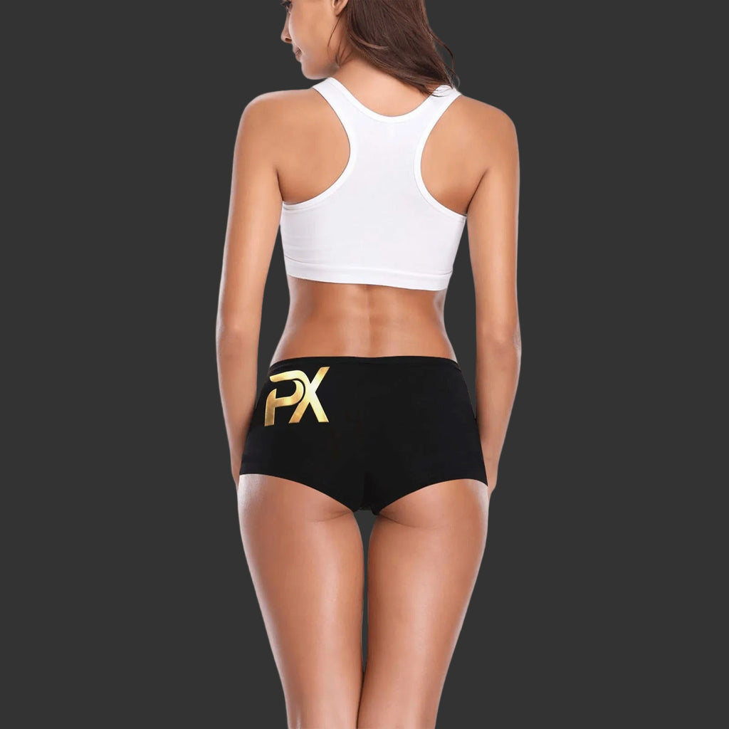 Woman standing wearing a white sports bra with black boy shorts that has the logo "PX" on them for PineappleXXclusive on the left upper butt cheek region.