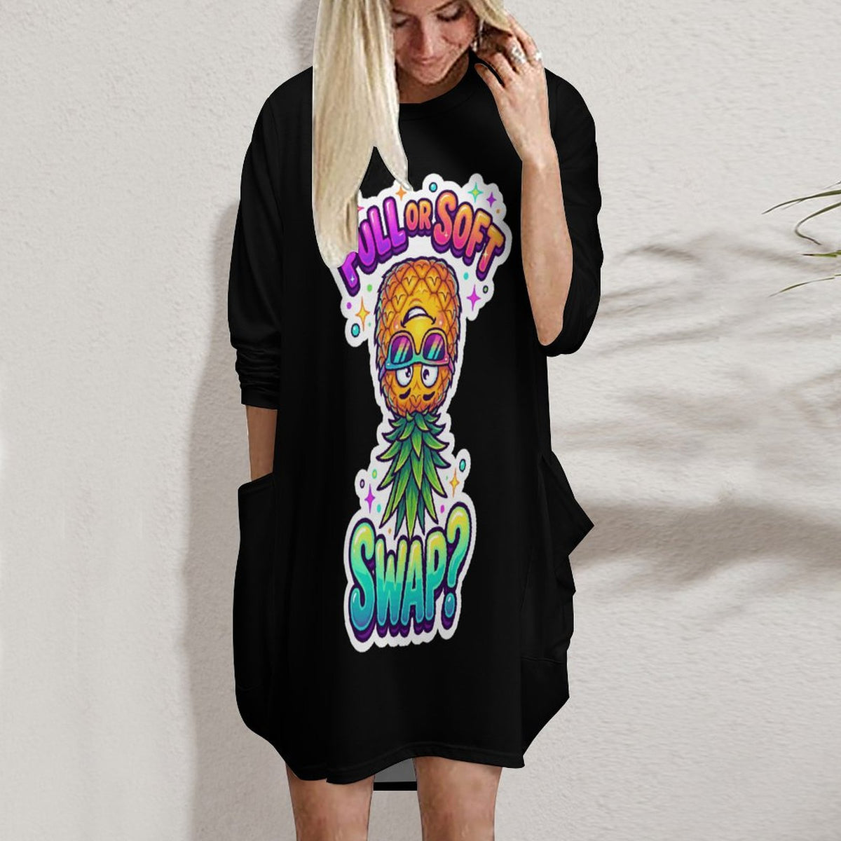 A woman wearing a black long-sleeve tunic dress with a colorful pineapple graphic on the front that reads 'I'll Be Soft SWAP?'.