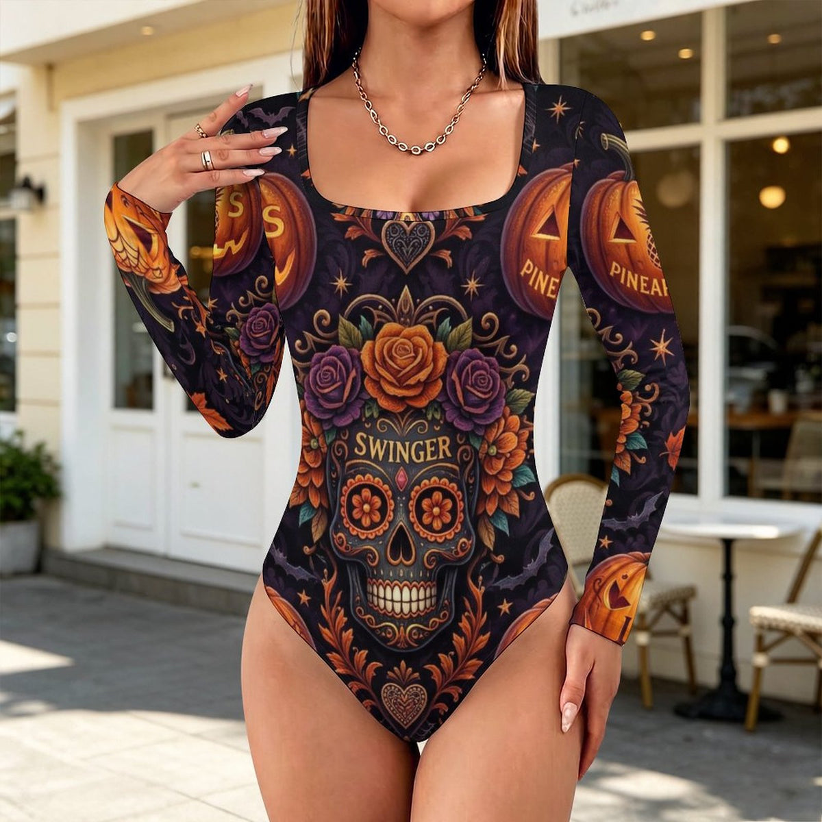 A woman modeling a long-sleeve one-piece swimsuit with a Day of the Dead sugar skull and pumpkin print, standing outdoors in front of a storefront.