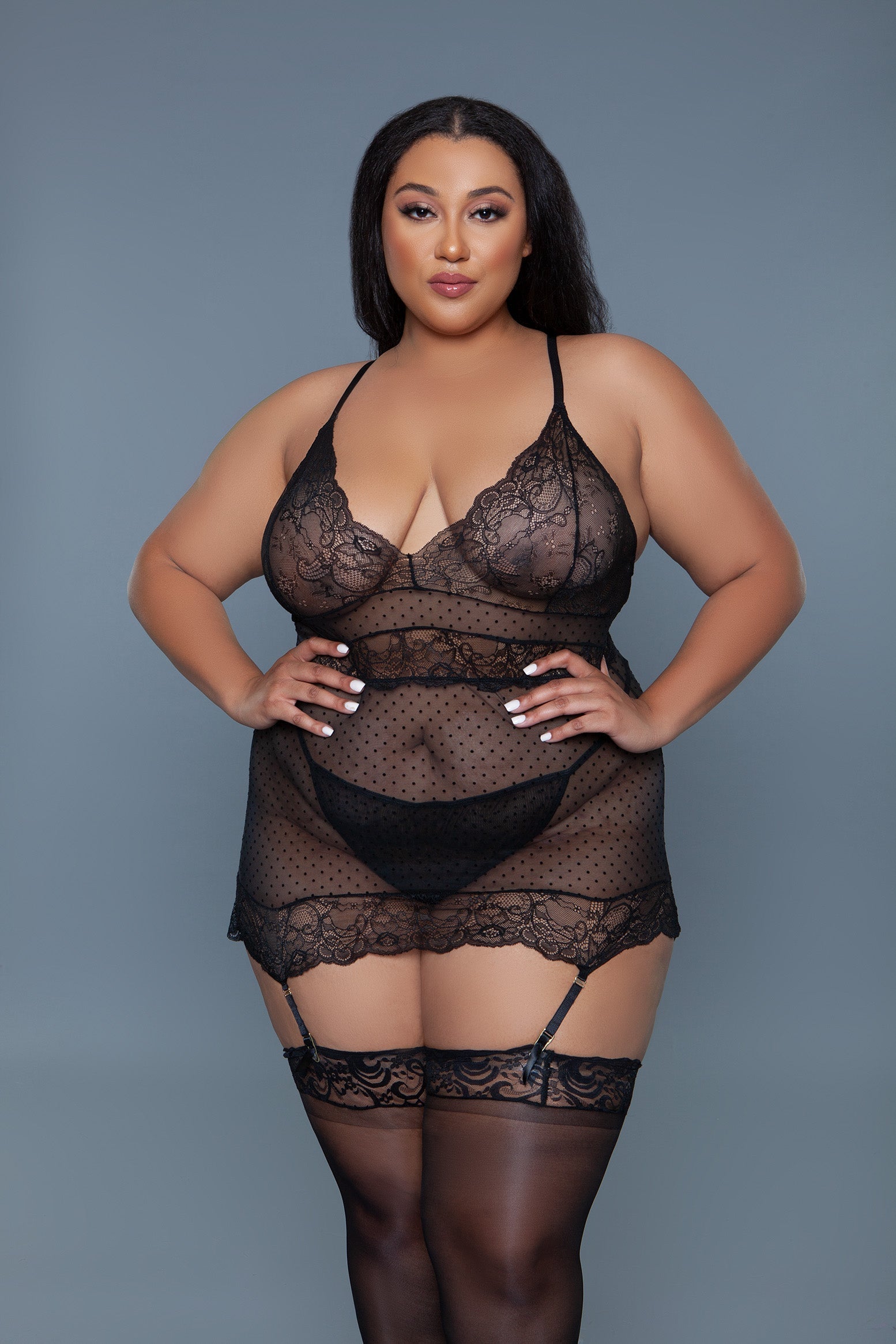 Woman wearing a black lace lingerie set against a gray background