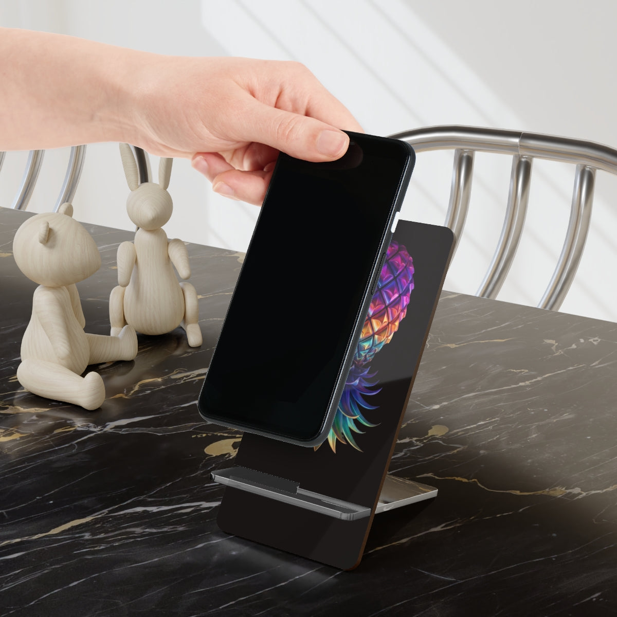 Colorful upside-down pineapple phone stand with a black background.