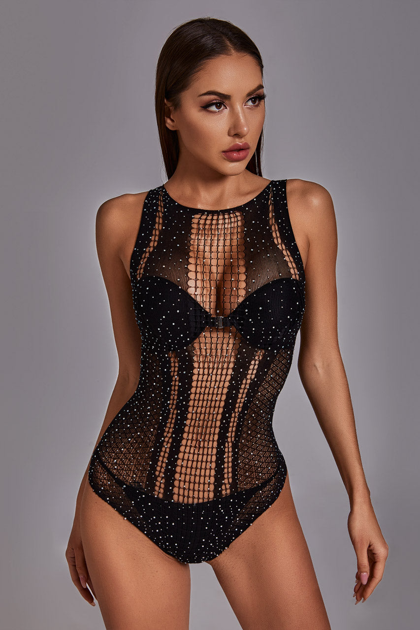 Model wearing a black mesh bodysuit with rhinestone embellishments on a gray background