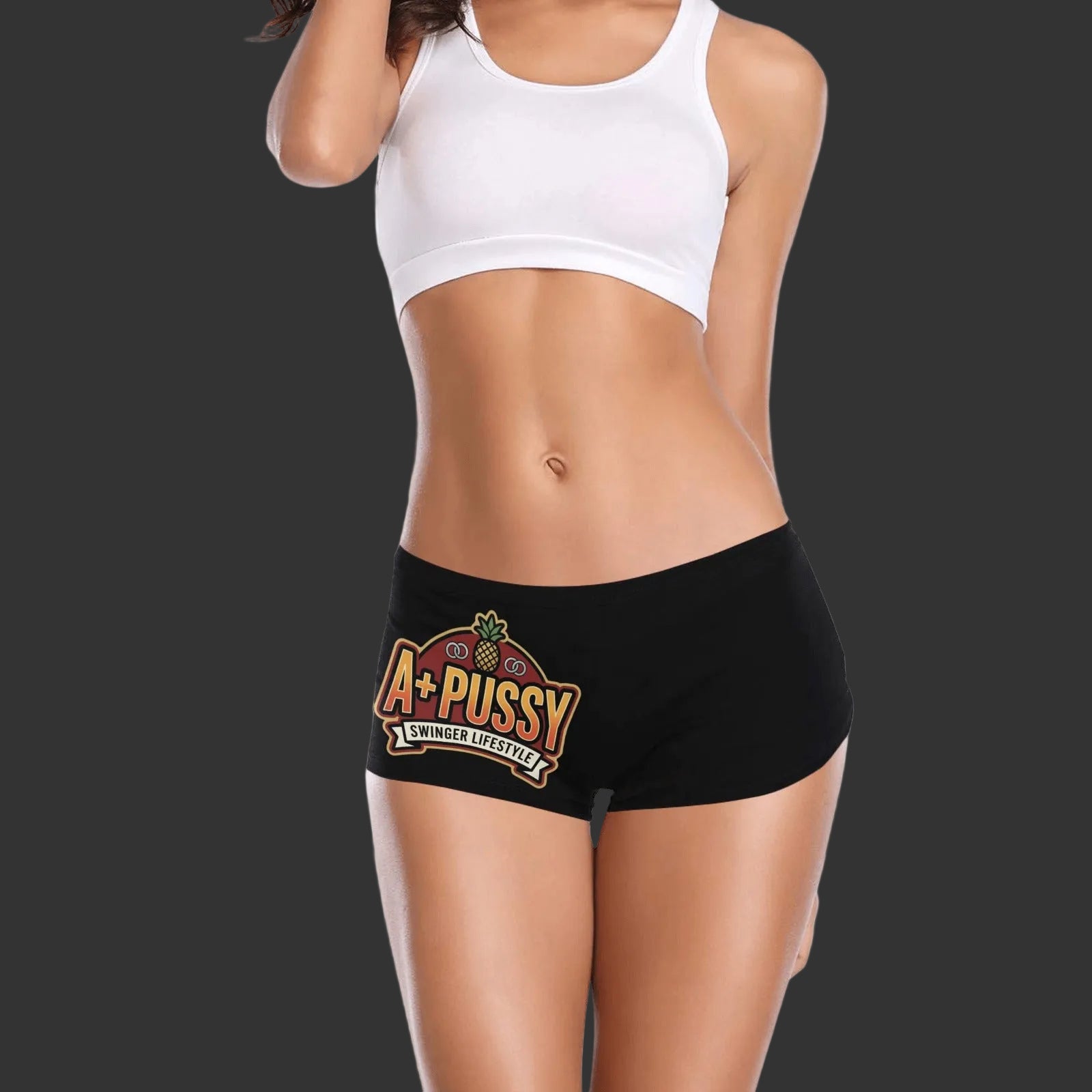 Woman wearing a white bra and black boy shorts that say "A+ Pussy" on the right leg of the shorts.