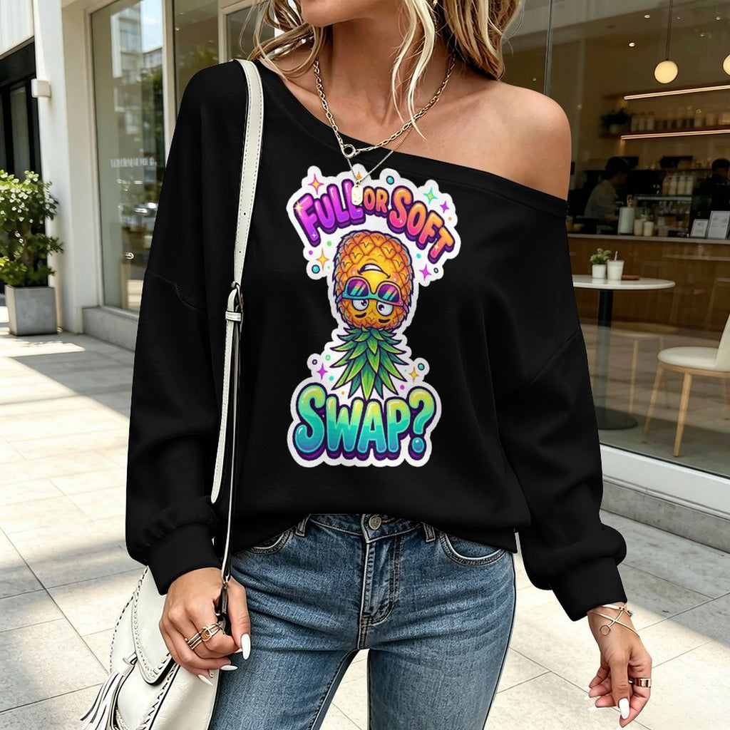 A woman wearing a black off-the-shoulder sweatshirt with a colorful pineapple graphic that reads 'FULL OR SOFT SWAP?' in bright gradient lettering, paired with blue jeans and a white shoulder bag, standing outside a shop.