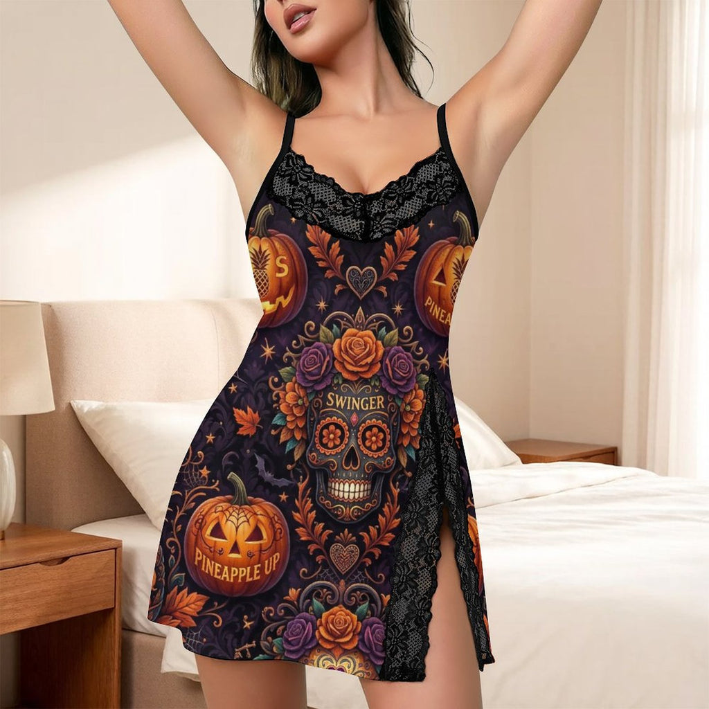 A woman wearing a black lace-trim mini slip dress with a colorful Day of the Dead Halloween print featuring sugar skulls, pumpkins, roses, and the words 'Swinger' and 'Pineapple Up', posed in a bedroom setting.