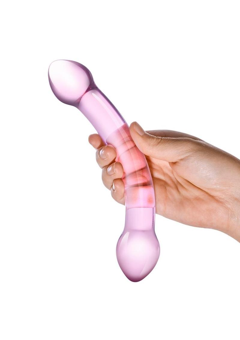 Pink handheld massager held in a hand against a white background