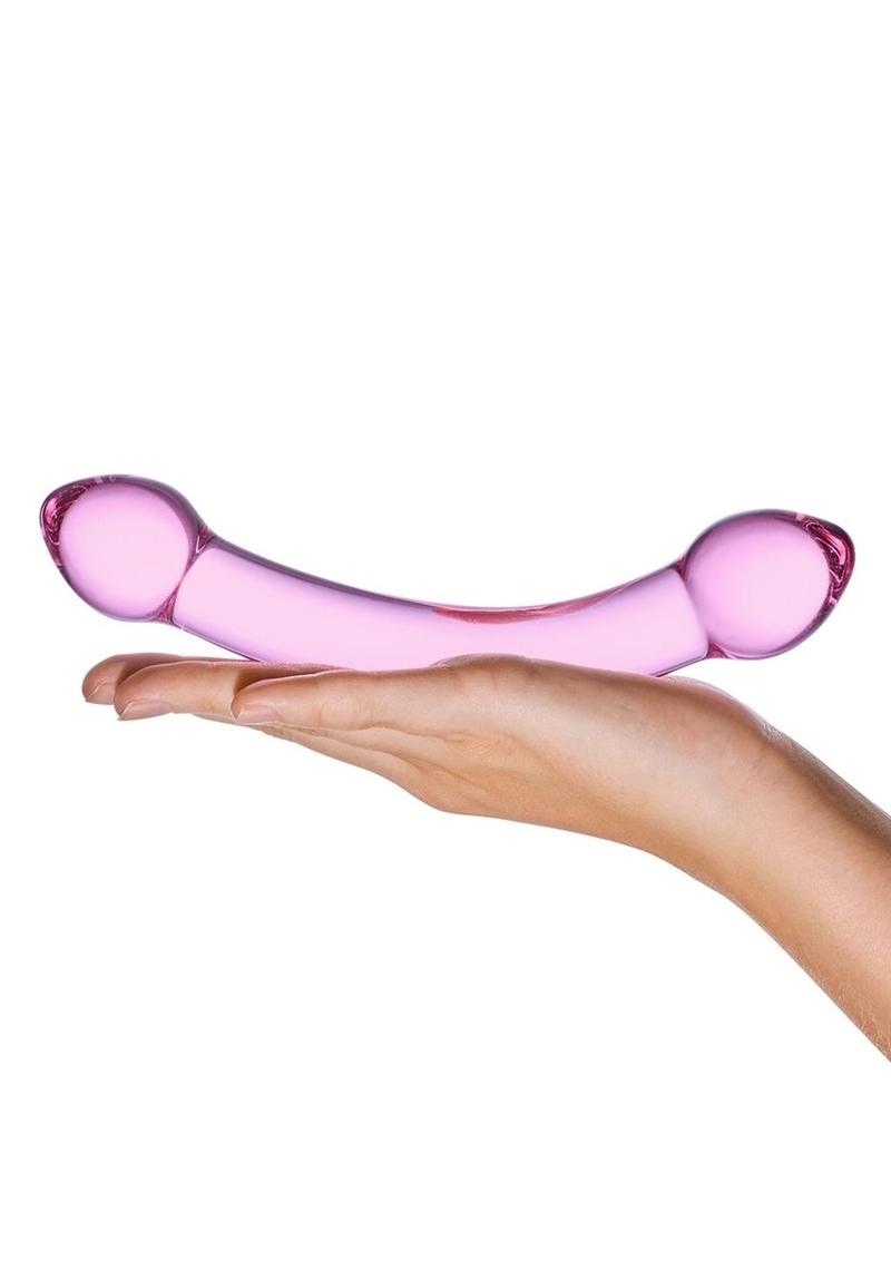 Pink glass object held in a hand against a white background