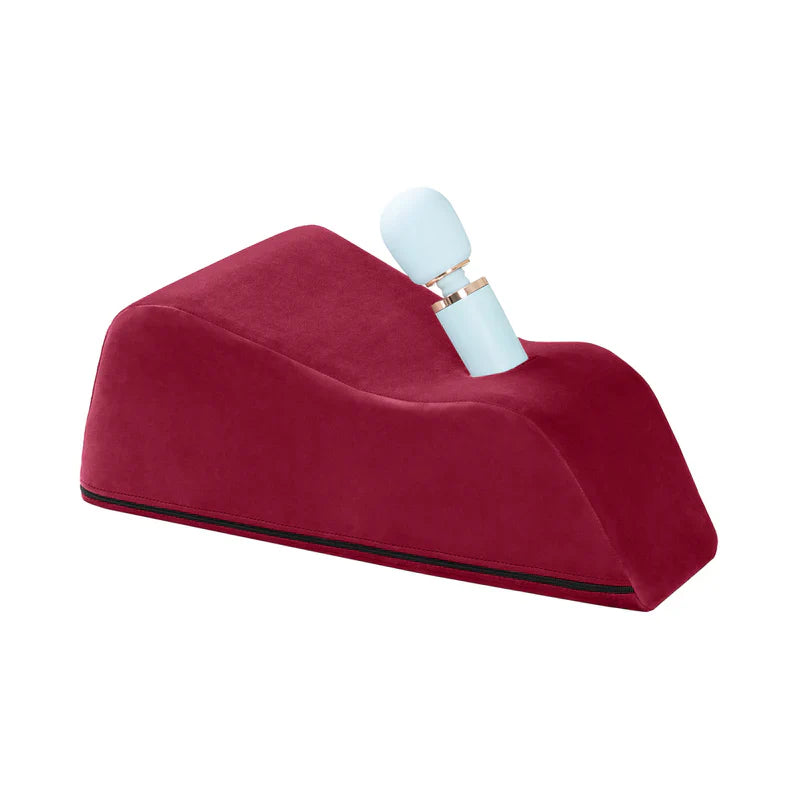 Red wedge pillow with a white and gold object on a white background