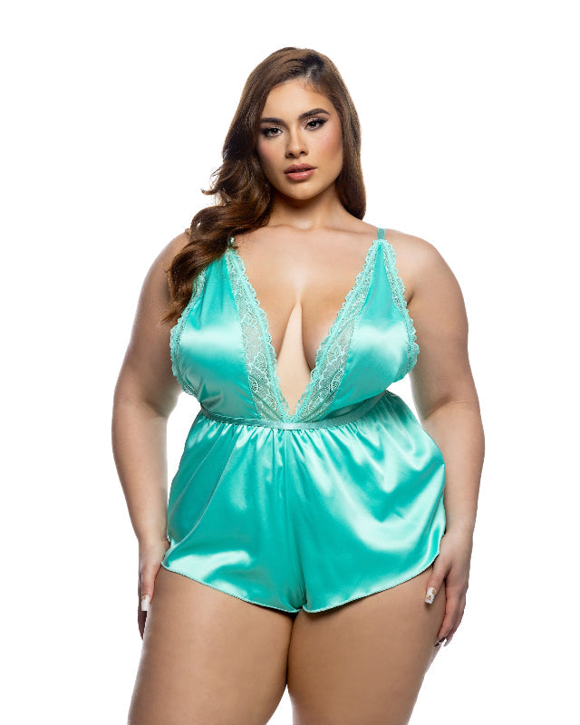 Woman wearing a turquoise satin romper with lace details on a white background
