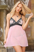 Woman wearing a pink nightgown with black lace details in an elegant setting.